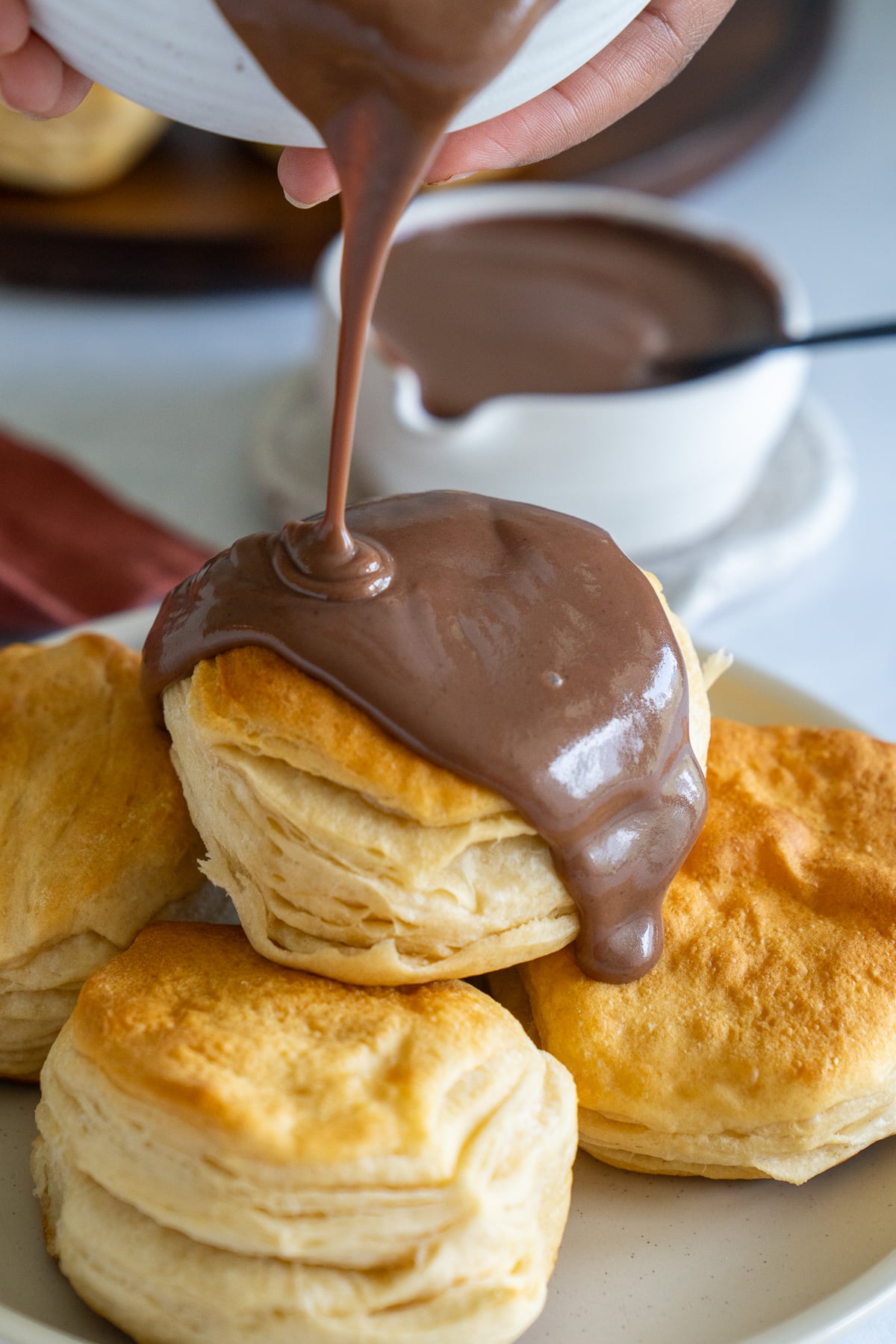 chocolate gravy being poured over biscuits