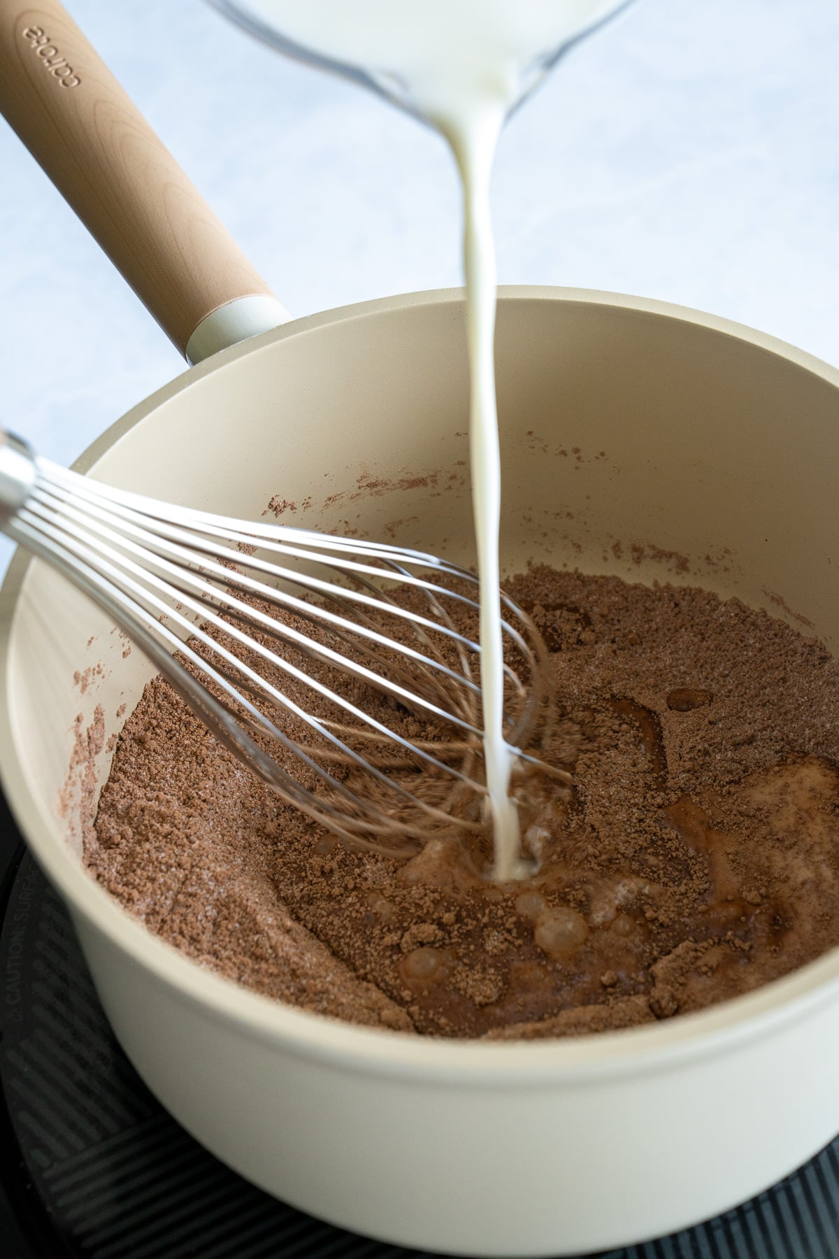 milk being whisked into cocoa powder and sugar in pot