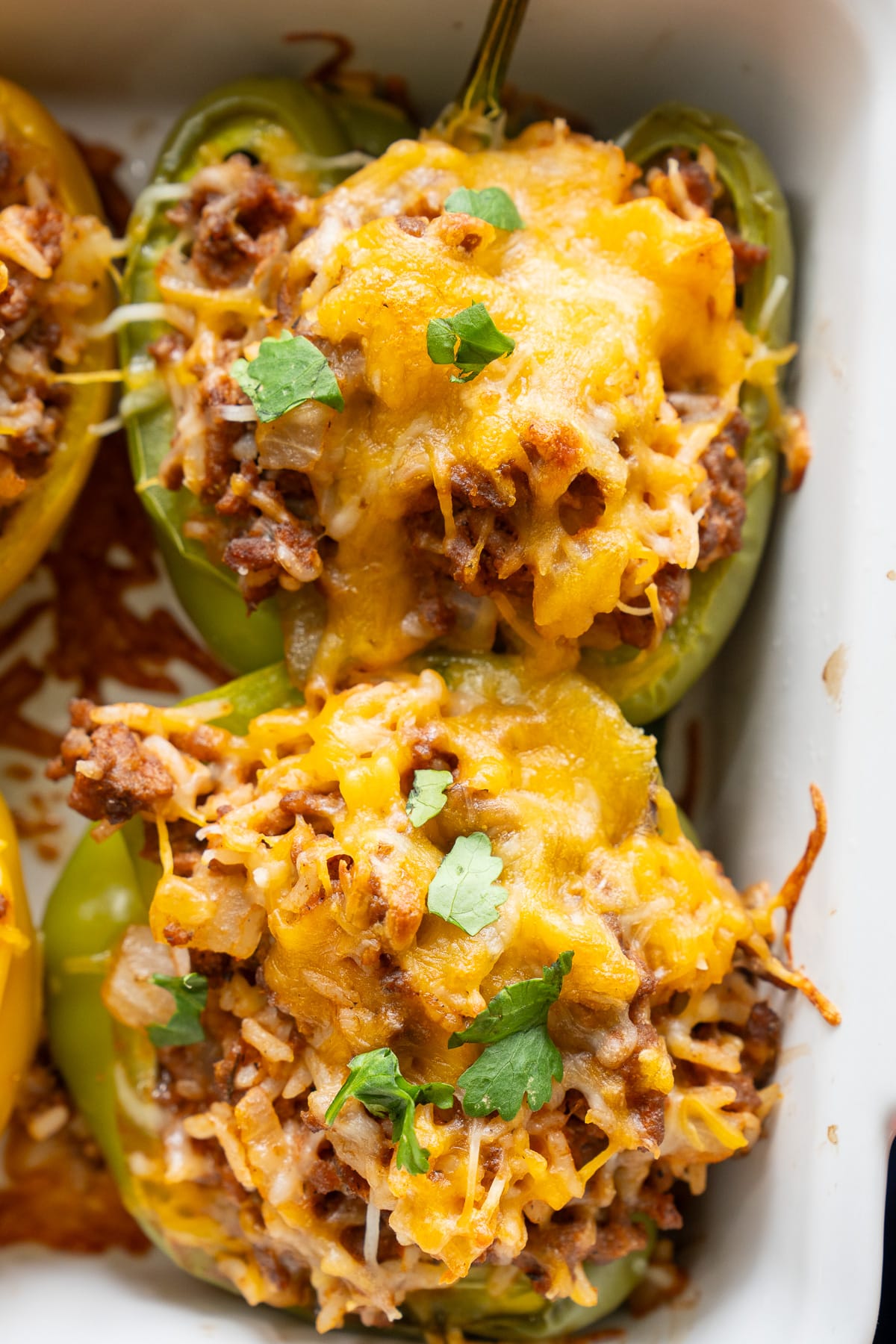 close up photo of bell peppers covered in cheese in baking dish