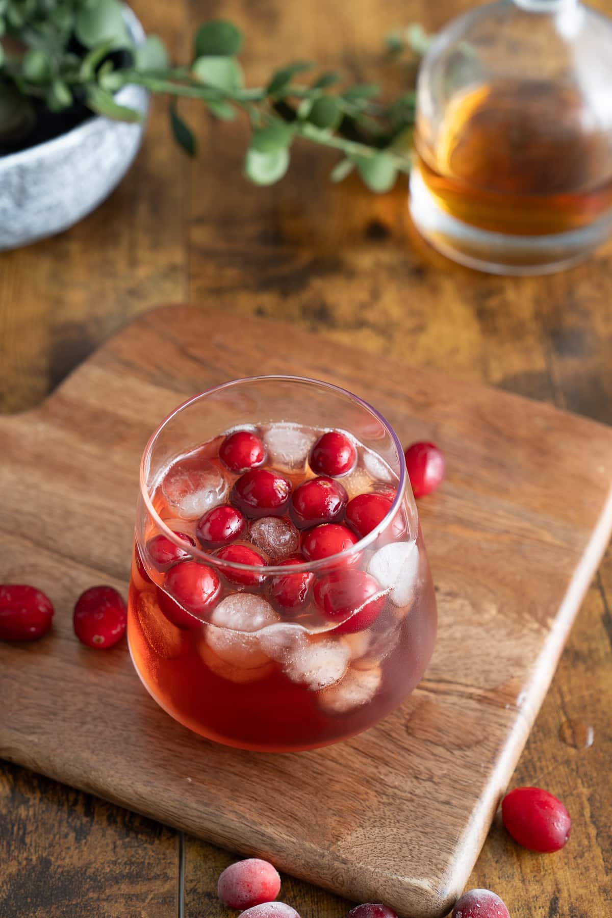 whiskey cranberry cocktail on board with cranberies around it