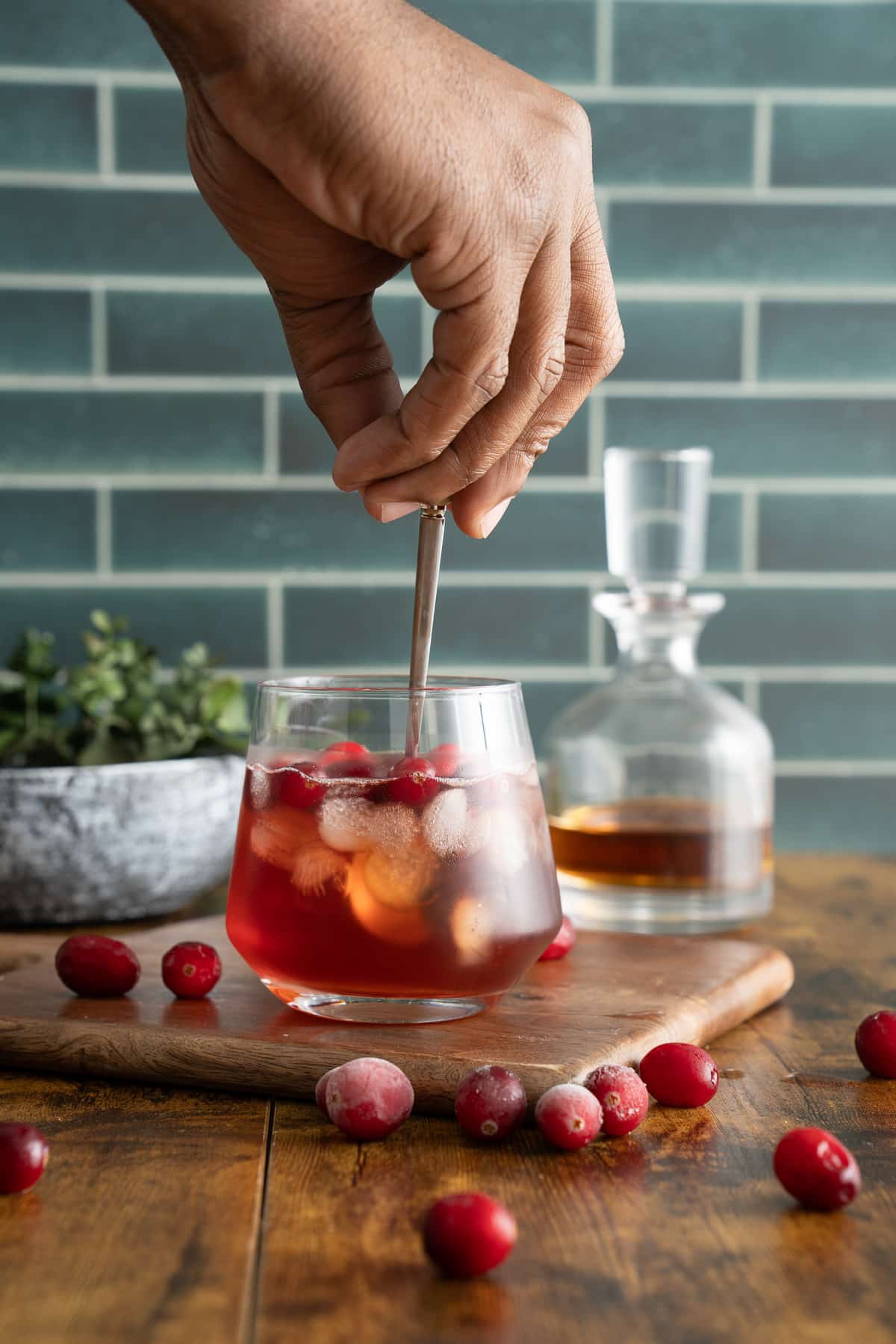 hand stirring whiskey cranberry cocktail