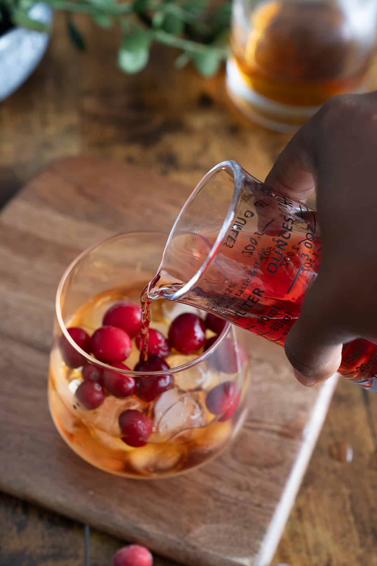 cranberry juice being poured into cocktail