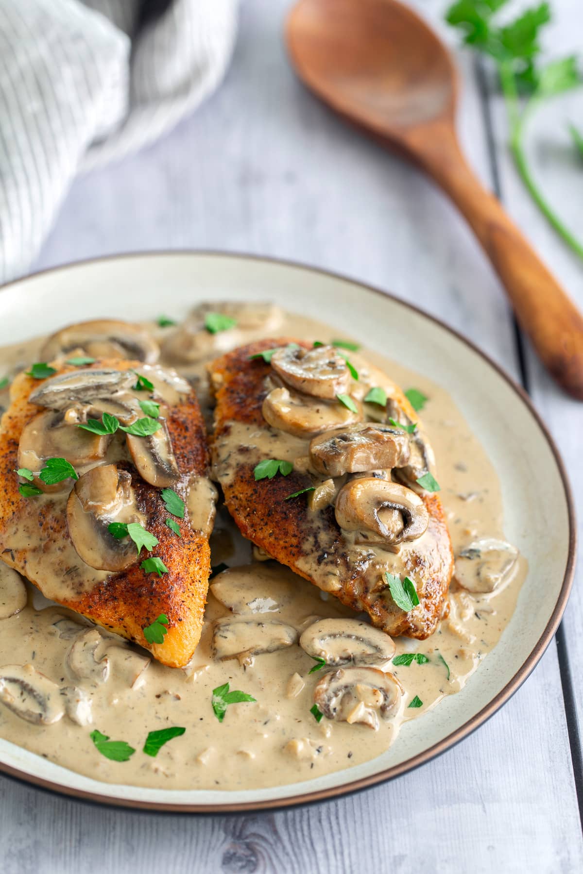 cream of mushroom chicken plated on white plate with napkin and spoon in the background