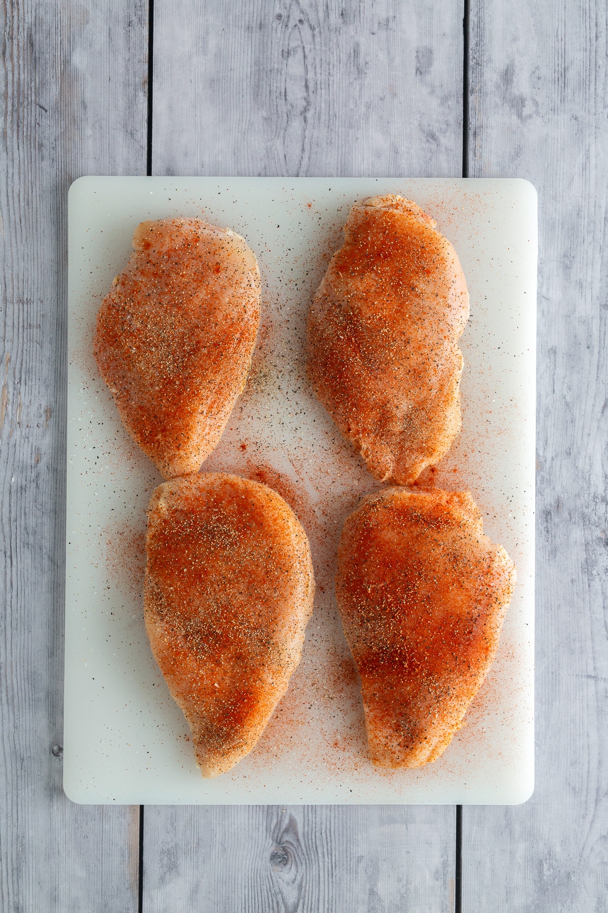 seasoned raw chicken breast on cutting board