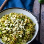 sauteed shredded brussels sprouts in white bowl with spoon on side