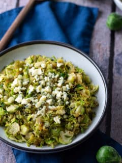 sauteed shredded brussels sprouts in white bowl with spoon on side