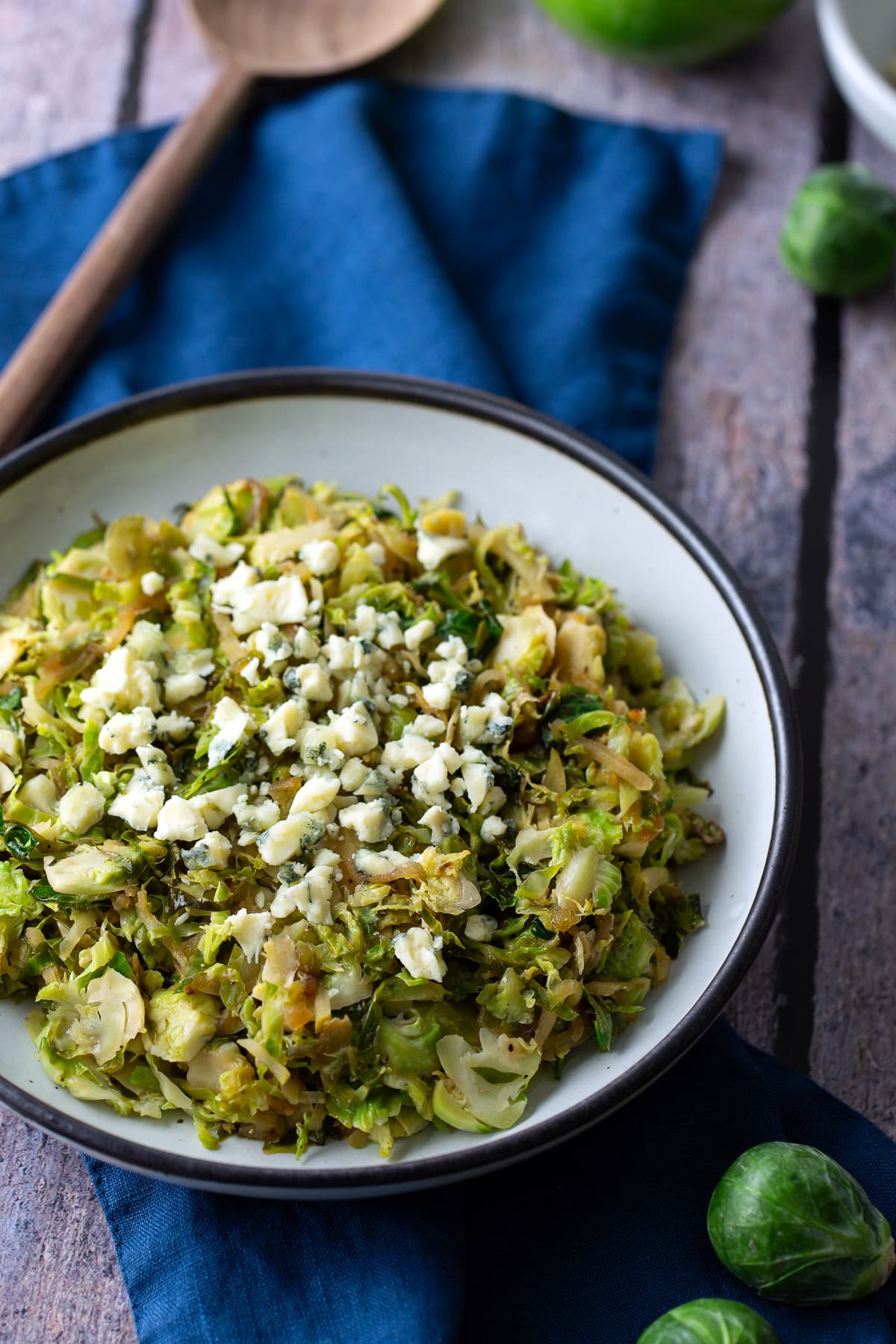 sauteed shredded brussels sprouts in white bowl with spoon on side