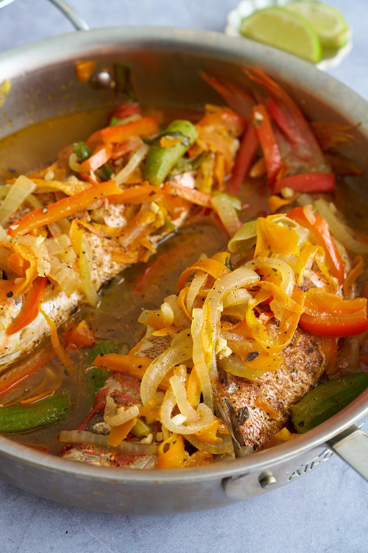 steamed fish in pan with cooked vegetables over top