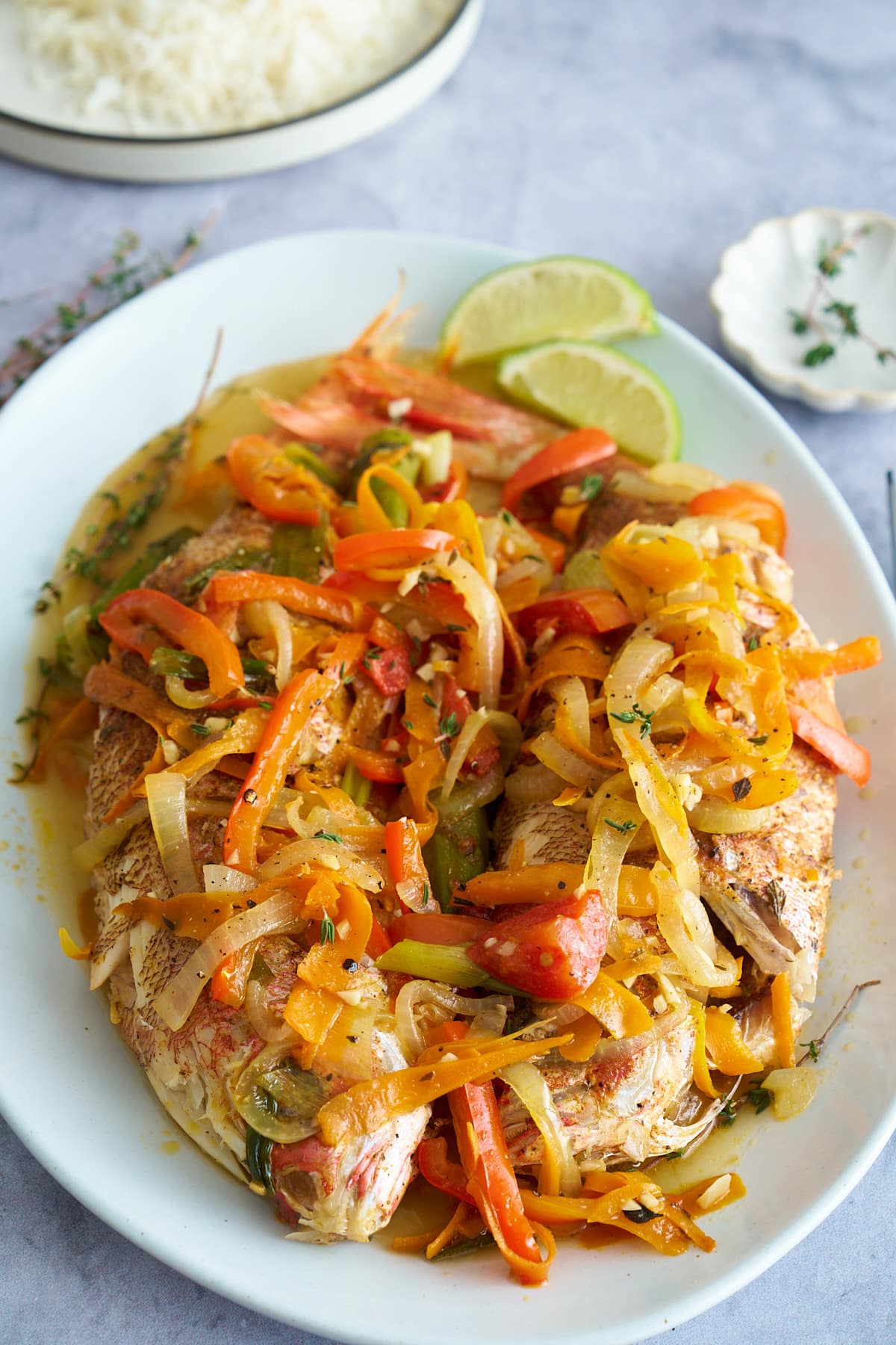 steamed fish covered in vegetables on white platter plate