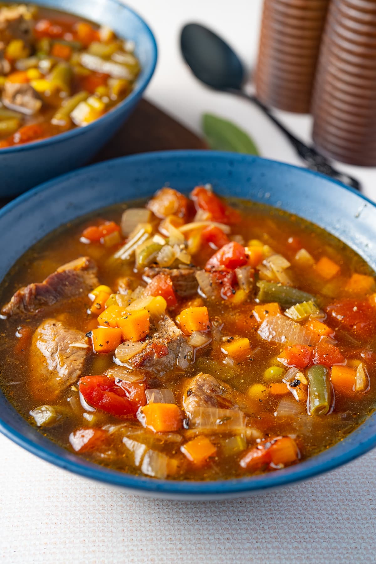 vegetable beef soup in bowl with spoon in background