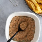 french fry seasoning in bowl with french fries on the side