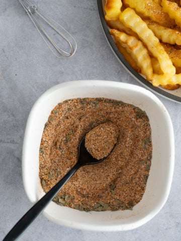 french fry seasoning in bowl with french fries on the side