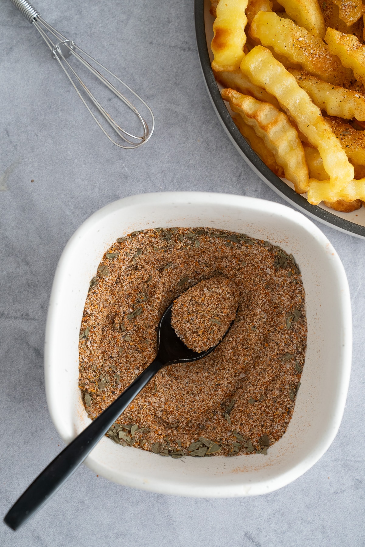 french fry seasoning in bowl with french fries on the side