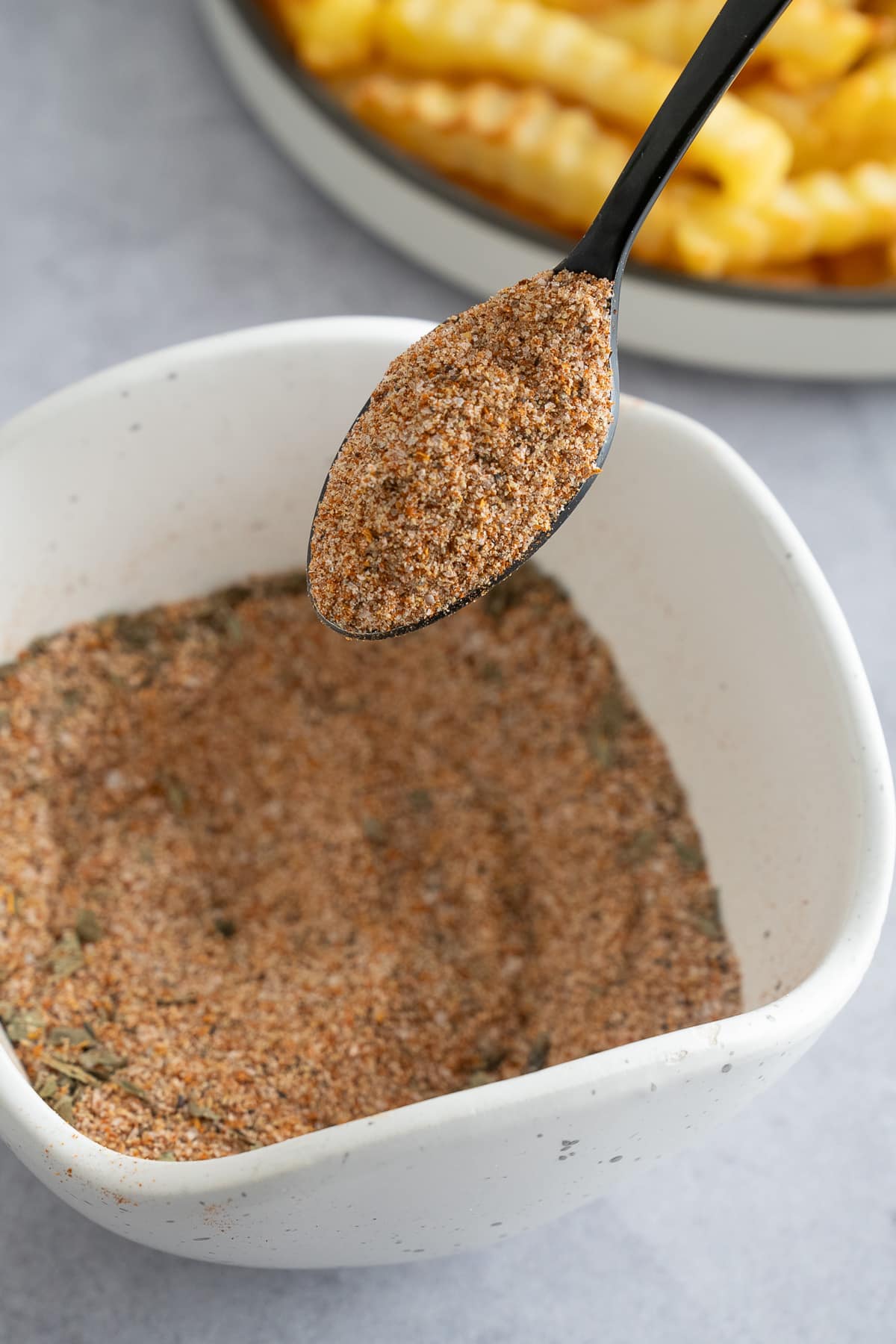 french fry seasoning in bowl with spoon mxing it up