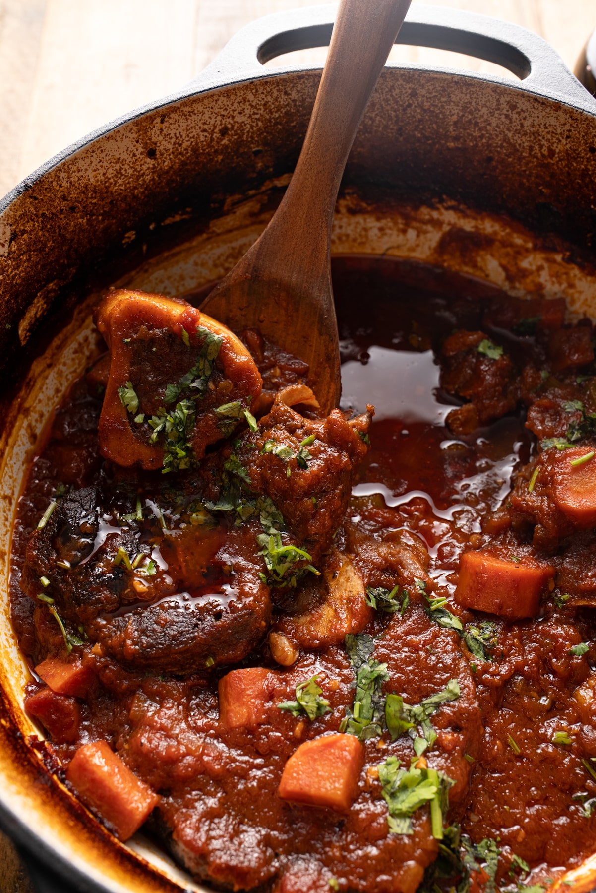 braised beef shanks in pot with spoon lifting a beef shank