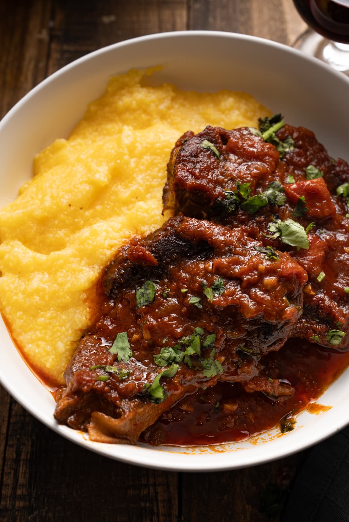 beef shank on plate woth polenta on side