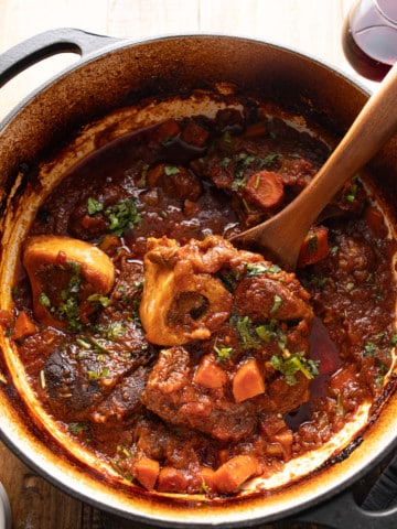 braised beef shanks in pot with spoon picking up beef shank