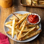 oven baked fries in plate with kecthup on side with red towel on side