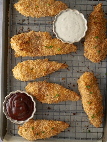 baked chicken tenders on rack with dipping sauces on the side