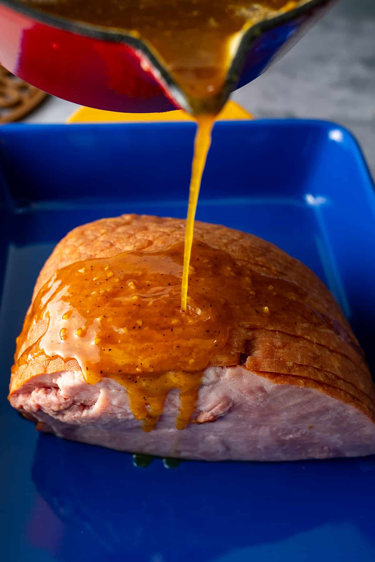 ham glaze being poured on ham prior to baking