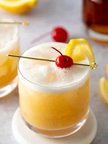 whiskey sour in glass with cherry on top