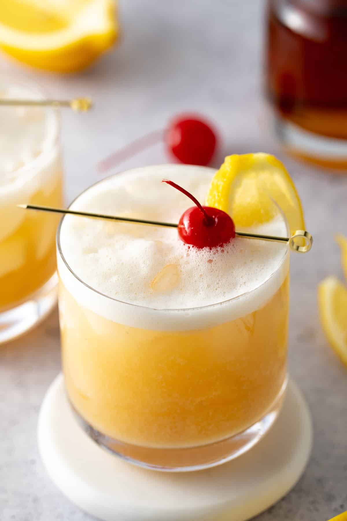 whiskey sour in glass with cherry on top